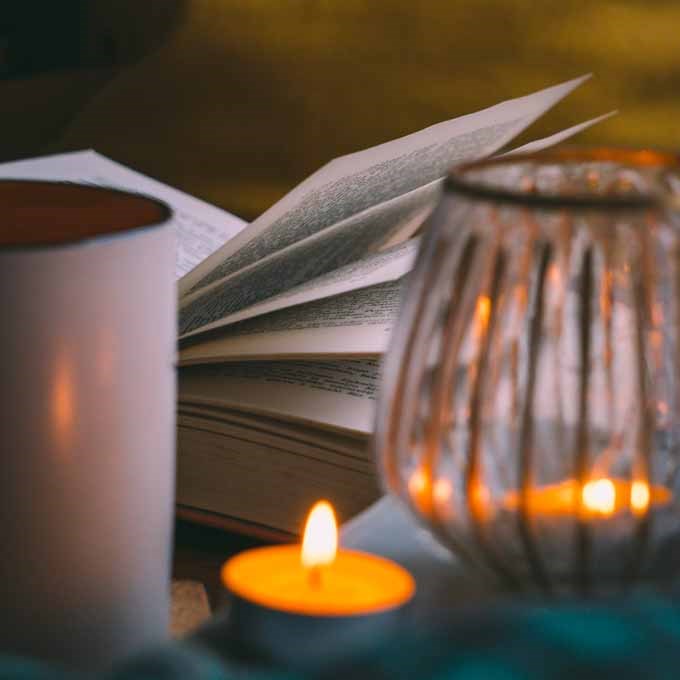 candle lightning a book and a cup of coffee creating a cosy atmosphere