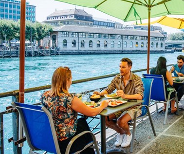people having lunch on a summer terrace by the river rhone in geneva