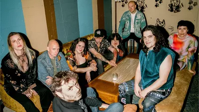 Un groupe de musique assis dans un bar autour d'une table. Il y a 9 personnes.