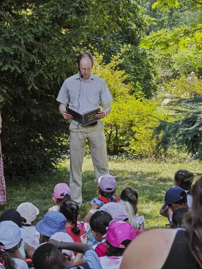 Science, nature, and literature “à la Jean-Jacques Rousseau” ! Enfants assis dans l'herbe à l'écoute du conteur-bibliothécaire