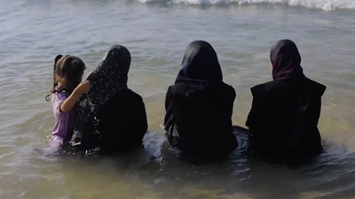 Des femmes habillées dans l'eau, prises de dos.
