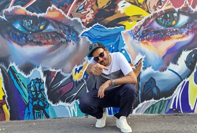 Un portrait de Dj Toots devant un tag coloré.