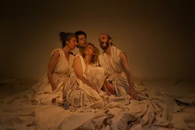 4 danseurs accroupis dans un amoncellement de dras blancs