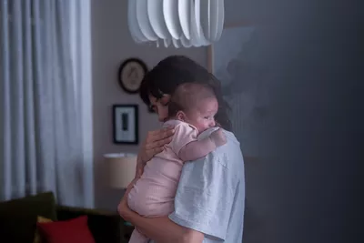 Ciné-dimanche X Everybody's Perfect : Un mundo para mi Femme tenant un bébé dans les bras dans une pièce de la maison.