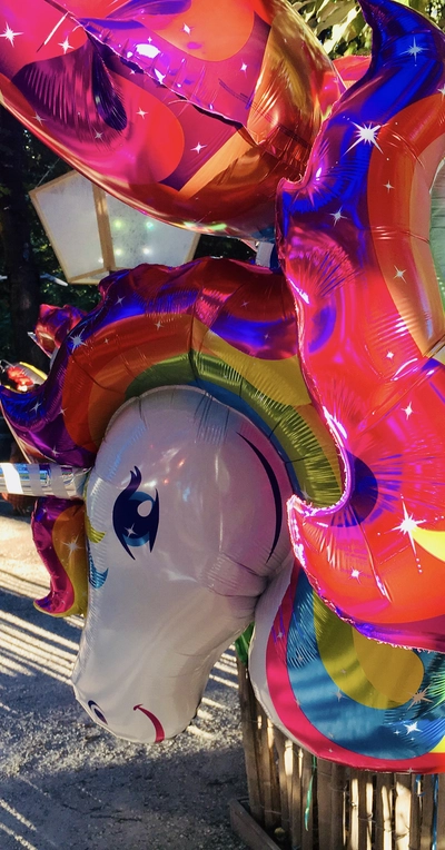 Louise et Anne vont en Louisiane Un tas de balons colorés, on voit en premier plan une licorne sur les tons fucsia et arc en ciel.