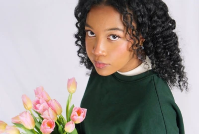 une image de l'artiste qui tient un bouquet de fleur