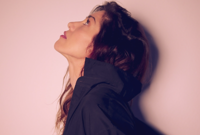 ELECTRIC PUMA C'est une photo en couleur de l'artiste sur un fond rose. Elle est de profil et regarde vers le haut.