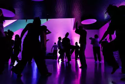 Common flow au MEG avec des personnes qui dansent sur une ambiance de lumière violette et bleue.