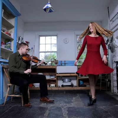 musicien et danseuse iralndais dans leur cuisine en train de jouer et danser