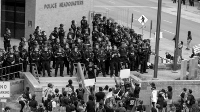 Des manifestants font face à de nombreux policiers, devant un hôtel de police.