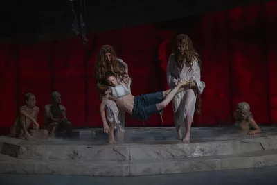 APRÈS MOI, LE DÉLUGE Une piscine en pierre est sur scène. Deux danseurs sortent de l'eau une femme inconsciente. Trois autres sont assis, à l'arrière-plan.