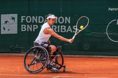 Swiss Open Geneva On voit sur cette image, une joueuse de tennis en fauteuil roulant en pleine action sur un court en terre battue.