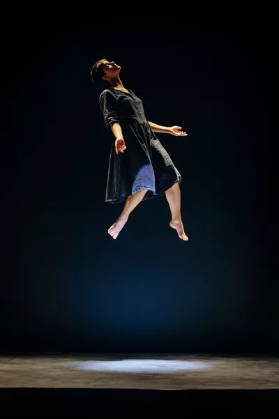 ON M'A TROUVÉE GRANDIE Sur scène, une femme flotte dans les airs, les yeux fermés et les bras ouverts.
