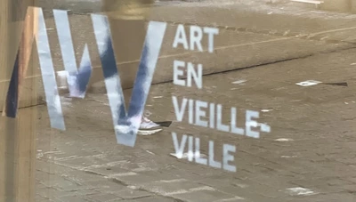 logo AVV sur une vitrine dans laquelle se reflète un enfant qui marche