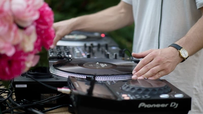 photo d'une platine, d'un DJ qui mixe et de fleurs festives