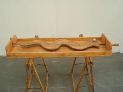 Jeu en bois avec un planche en bois et une poignée qui permet de guider une bille en bois sur un parcours sinueux.