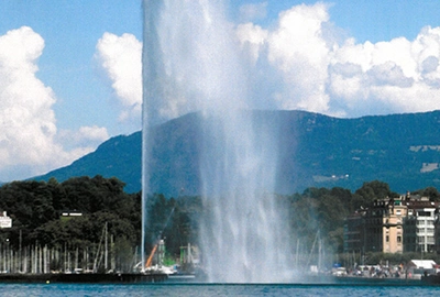 Vue du lac avec jet d'eau et quai devant une montagne