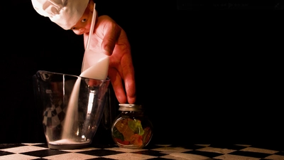 Une main-marionnette qui verse du sucre et cuisine