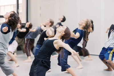 Un groupe de danseurs lève les yeux au ciel les bras écartés