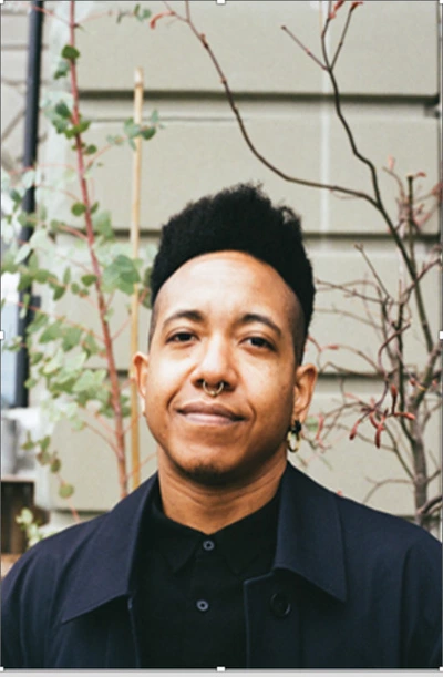 Une personne souriant face à l’objectif vêtu d’une chemise noire