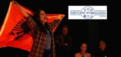 Une personne sur scène tient un drapeau rouge avec un aigle noir, éclairée par une lumière chaude. Derrière elle, d’autres personnes sont assises autour d’une table, dans l’ombre. En haut à droite, un logo noir et blanc est visible, et en bas de l’image, un bandeau avec des logos et du texte de l’Université de Genève.