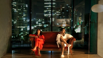 Une femme et un homme assis sur un canapé. Ils sont dans un building