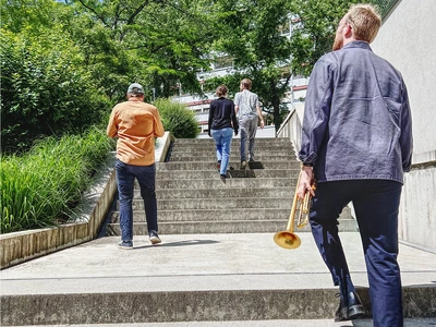 Les quatre musicien.ne.s de dos montant des escaliers