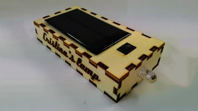 Le résultat de l'atelier, posé sur une table. C'est une boîte en bois avec une led qui dépasse et une batterie solaire sur le dessus.