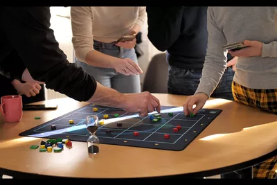 Planet C-Play Again?® Sablier et joueurs plaçant des pions sur un plateau
