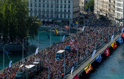 Sur cette image on peut voir une foule de personnes allant sur le pont du mont blanc à Genève. Au milieu de la foule on remarque des bus qui diffuse de la musique.