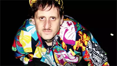 Un homme en habits colorés sur un vélo, il fait nuit sur l'image.