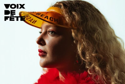 Un portrait de l'artiste Ooralise, cheveux détachés, avec un boa rouge sur les épaules.