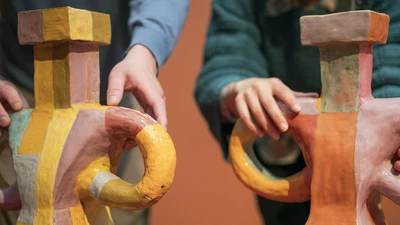 Deux personnes touchent la surface d’œuvres en céramique dans l'exposition "Marie Ducaté. Simultanés"