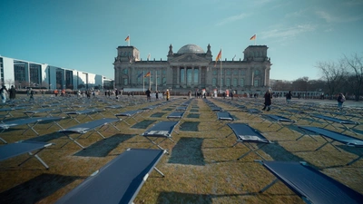 Des lits dépliants recouvrent la plaine devant le Palais du Reichstag à Berlin.
