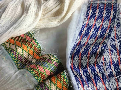 Gros plan d’une netela blanche avec des motifs géométriques et colorés.