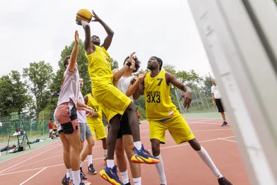 UNISPORT DAY Cette image capture une action de jeu intense lors d'un match de basket-ball 3x3 en extérieur.
Un joueur s'élève très haut dans les airs pour tenter un tir en suspension.