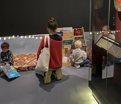Femme et des enfants installés près de livres dans l'exposition permanente