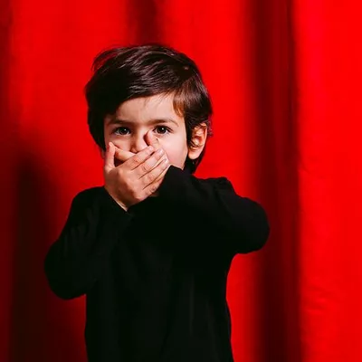 Atelier Théâtre : du livre à la scène avec Clémentine Le Bas, comédienne, à la Bibliothèque de la Cité Un enfant se met les mains devant la bouche l'air surpris. Il se tient devant un rideau de théâtre rouge fermé