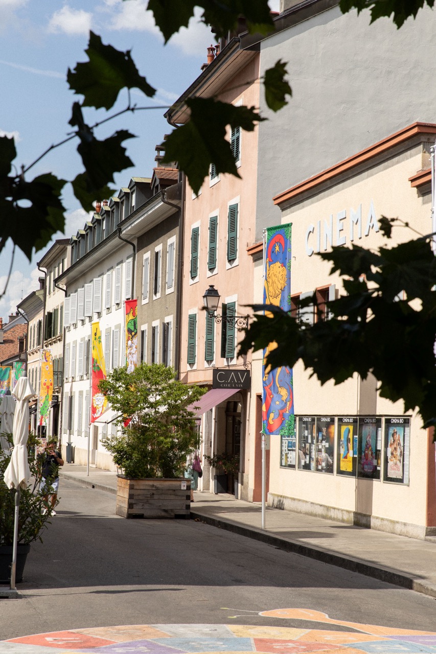 Rue de Carouge bordée de banderoles colorées et d'une enseigne de cinéma historique