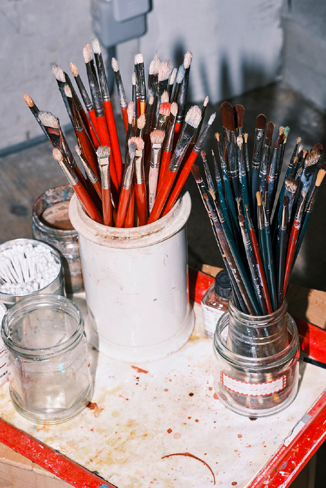 Pots de pinceaux aux poils rouges et noirs dans un atelier d'artiste