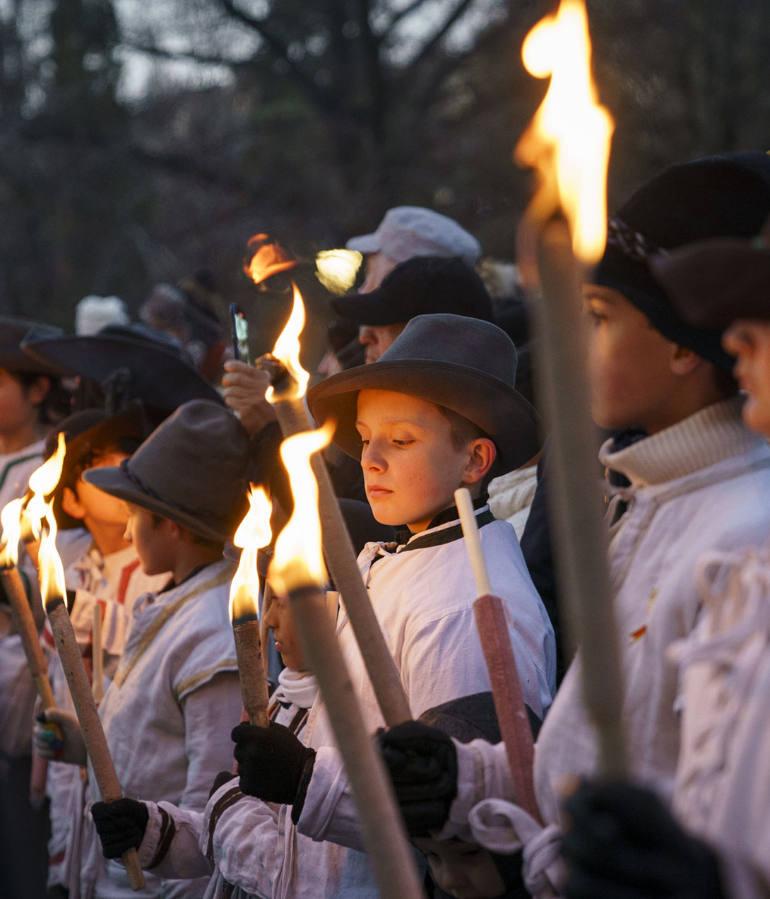 Kinder in historischen Kostümen und Filzhüten mit brennenden Fackeln für den Escalade-Umzug in Genf