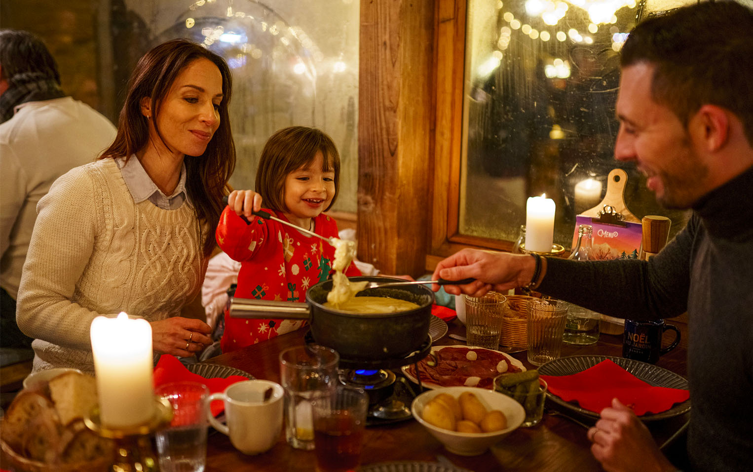 A family sharing a cheese fondue by candlelight in the Chalet à Fondue